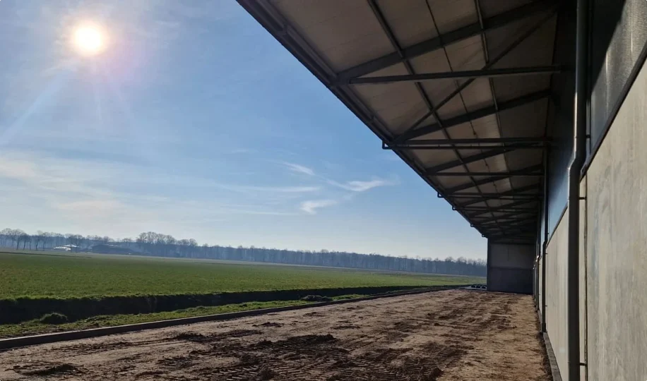 Zijkant van bedrijfshal met uitzicht over weiland
